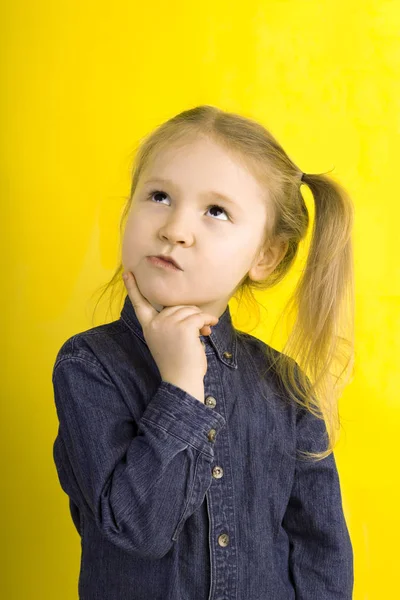 Little girl thinks. emotions. on yellow background Stock Image