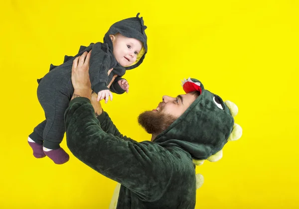 funny dad and daughter in dragon costume. on a yellow background