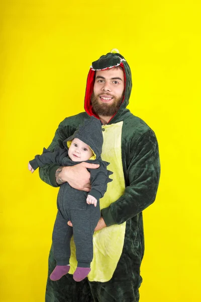 funny dad and daughter in dragon costume. on a yellow background