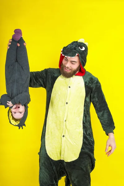 funny dad and daughter in dragon costume. on a yellow background