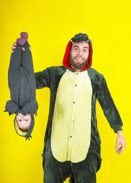 funny dad and daughter in dragon costume. on a yellow background