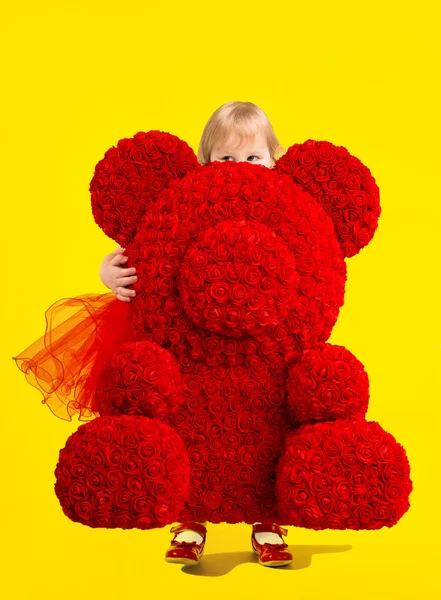 Petite fille avec un énorme ours dans sa stature de roses. cadeau ours — Photo
