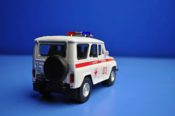 Çocuklar ve yetişkinler ilk yardım - ambulans mavi bir arka plan üzerinde için oyuncak metal araba