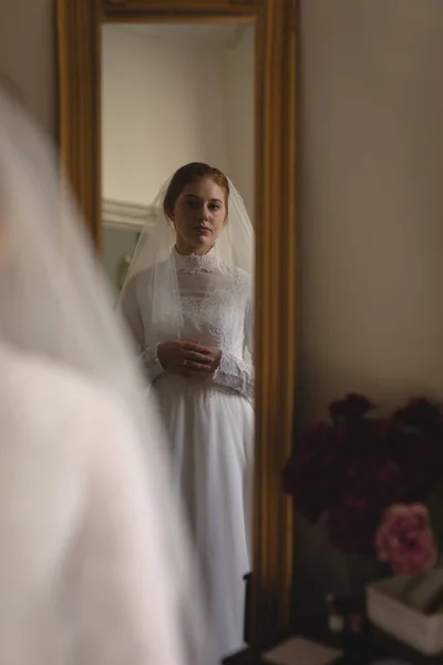 白人新娘婚纱礼服和面纱看着镜子在老式精品店 — 图库照片