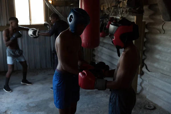 フィットネス スタジオで若い男性のボクサーを支援トレーナー — ストック写真
