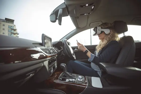 車でデジタル タブレットと仮想現実のヘッドセットを使用して女性管理職の側面図 — ストック写真