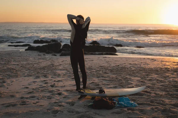 黄昏时分冲浪者站在沙滩上的后景色 — 图库照片