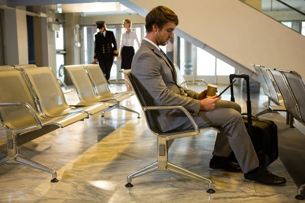 空港ターミナルで待っているエリアでデジタル タブレットを使用するビジネスマン — ストック写真