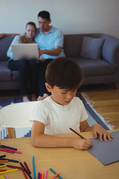 Pozorný Chlapec Výkres Dokumentu Zatímco Jeho Rodiče Pomocí Přenosného Počítače — Stock fotografie