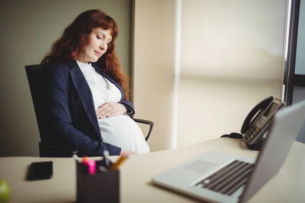 怀孕的女商人触摸肚子在办公室 — 图库照片
