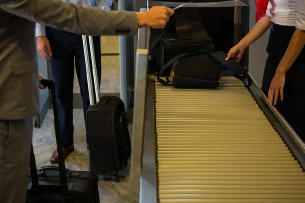 女性工作人员在机场传送带上检查乘客行李 — 图库照片
