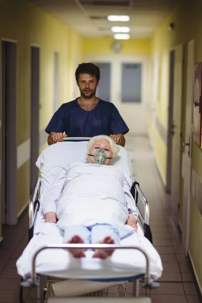 Ward Menino Empurrando Paciente Sênior Maca Corredor Hospital — Fotografia de Stock