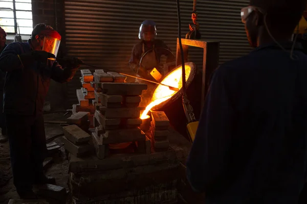 工人将熔融的金属从烧瓶倒进铸造厂的模具中 — 图库照片