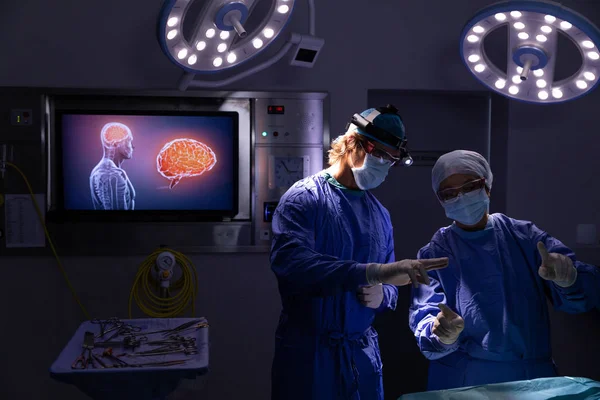 医院手术室手术时 外科医生在灯光和数字屏幕上互相交谈的正面看法 — 图库照片