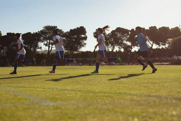 阳光明媚时 不同女足球员在运动场上奔跑的低角度视角 — 图库照片