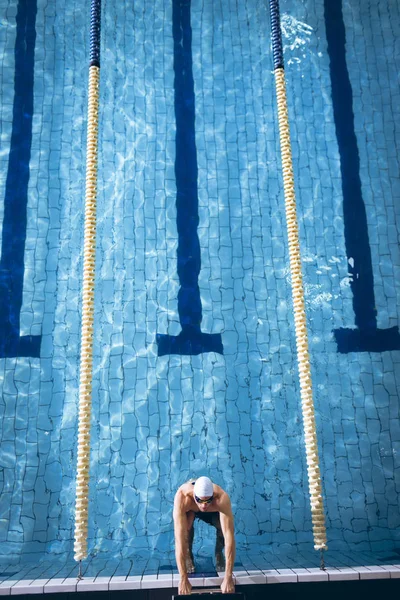 白い水泳帽とスイミングプールの側面に持つゴーグルを身に着けている男性白人水泳選手の高角図 — ストック写真