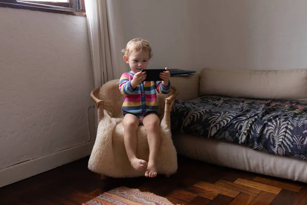 Передний Вид Кавказского Ребенка Сидящего Кресле Держащего Смартфон Босиком — стоковое фото