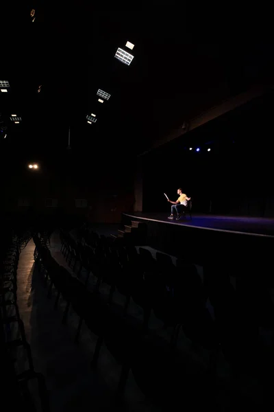 公演前に準備をし 舞台上で椅子に座り 台本を持って自分の役を練習する空の高校生の白人の十代の男性の高校生の側面図 — ストック写真