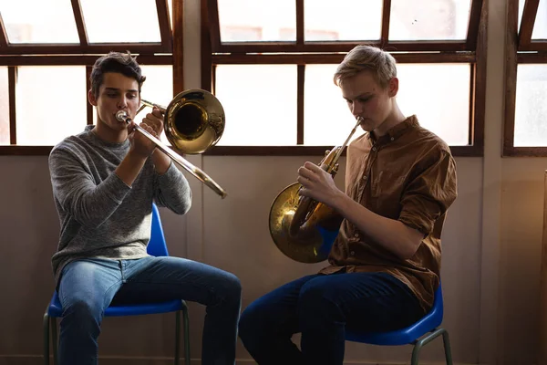 Hvite Tenåringsgutter Sitter Foran Vindu Spiller Trombone Valthorn – stockfoto