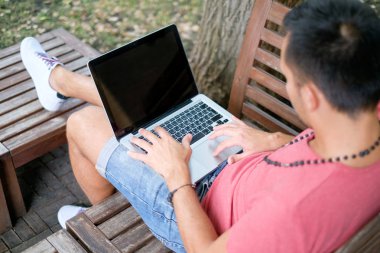 Bir adam bir bankta oturur ve bir dizüstü bilgisayarda yeni bir blog yazısı yazıyor