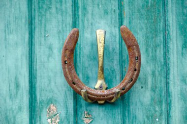 Eski ve paslı bir at nalı ev yapımı bir kanca açık havada mavi boya ile boyanmış ahşap kurullarının bir duvara asmak