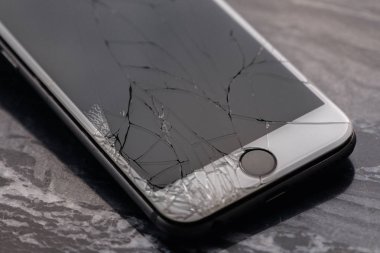 Kırık ve kırık akıllı telefon ekranı. Kırık bir akıllı telefon, monitörü onarmadan ve değiştirmeden önce masanın üzerinde yer alır. Kırık matris.