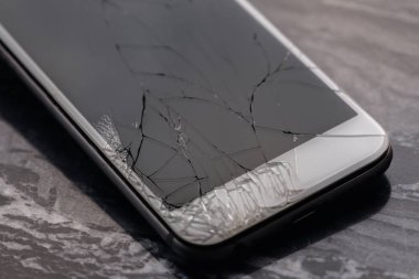 Broken and cracked smartphone screen. A broken smartphone lies on the table before repairing and replacing the monitor. Broken matrix. Close-up.