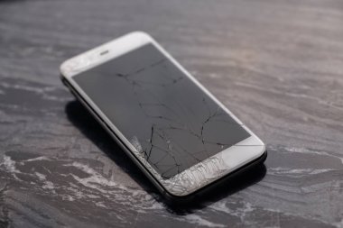 Broken and cracked smartphone screen. A broken smartphone lies on the table before repairing and replacing the monitor. Broken matrix. Close-up.