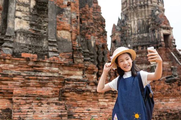 可爱快乐的微笑的旅游女孩在笏柴瓦的智能手机肖像照片是一个佛教寺庙在大城府历史公园 旅游概念 — 图库照片