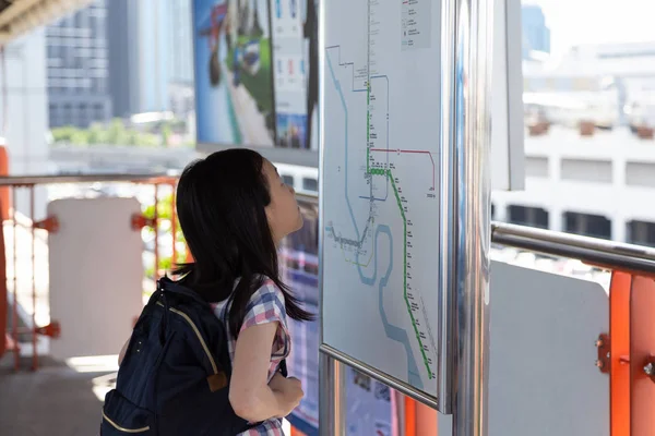 Asian girl orientating herself on the public transport map,Student looks at maps with public transport for travel in the big city,Search transport links on map urban transport