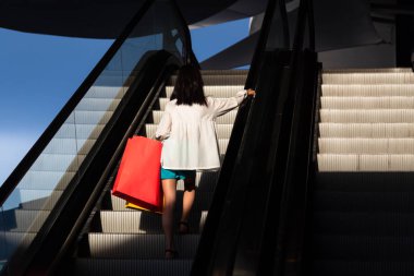 Bir mağazada alışveriş sonra bir yürüyen merdiven üzerinde Asyalı kız