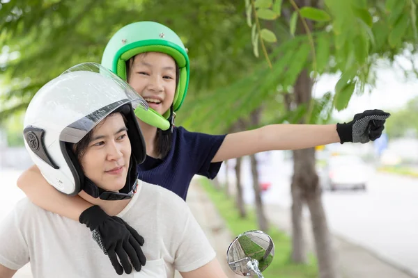 Mother and daughter traveling on motorcycle,motorcyclist wearing safe helmet before travel on motorcycle as accident prevention,safety riding concept.