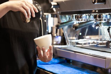 Süt dökme ve taze kapuçino sırasında sabah kahve makinesi kahve dükkanında önünde duran hazırlama kadın barista closeup görüntü 