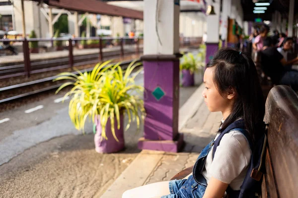 Chica asiática está sentada esperando a que los padres vuelvan a casa en la estación de tren, chica deprimida, distraída — Foto de Stock