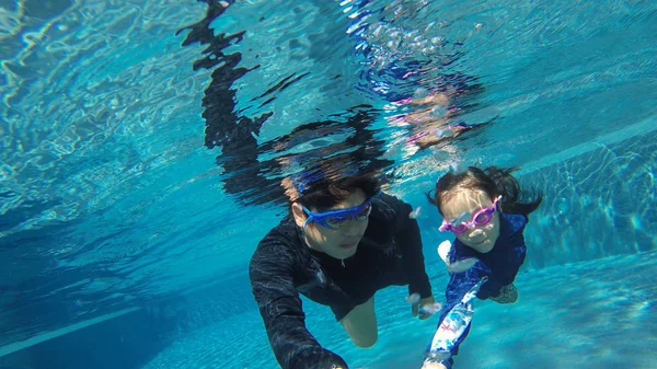 Vader en dochtertje zwemmen samen op vakantie in zwembad, gelukkig Aziatisch meisje leren zwemmen onder water in een zwembad met coach, zomer familie vakantie met kind, ontspannen, leuke activiteit — Stockfoto