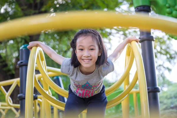 Asiatisches kleines Mädchen spielt auf einem Spielplatz im Freien und schaut in die Kamera im Park, Sommer, Urlaubskonzept — Stockfoto