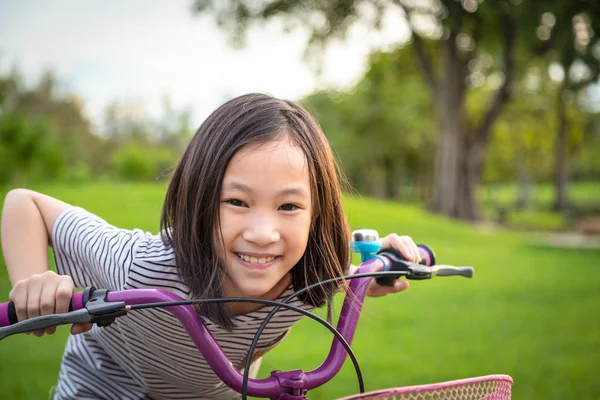 Asijská dívka na kameru, usmívající se roztomilý na kole v přírodě parku, dítě cvičení v přírodě ráno, koncept zdravého životního stylu — Stock fotografie