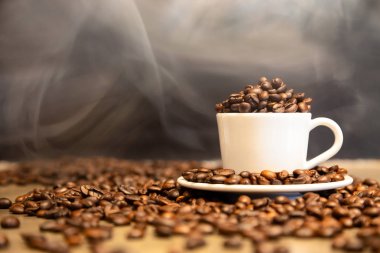 Sıcak espresso bir fincan kavrulmuş kahve çekirdekleri, arabica kahve çekirdekleri ve robusta kahve çekirdekleri karışık, orta koyu kavrulmuş bir kafe dükkanında siyah duvar arka planda kavrulmuş, espresso içmek için, sıcak buhar ve sabah duman, kopya alanı