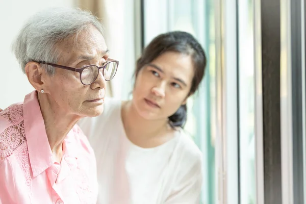 Mujer anciana con síntomas depresivos necesitan cuidado cercano, asiática joven cuidadora de apoyo, paciente de Alzheimer — Foto de Stock