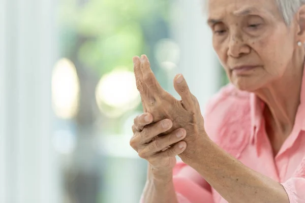 एशियाई बूढ़ी महिला अपने हाथ की मालिश कर रही है, हाथ में दर्द, आर्थराइटिस, साइबरबेरी या परिधीय न्यूरोपैथी से पीड़ित बुजुर्ग महिला — स्टॉक फ़ोटो, इमेज