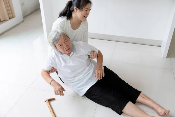 Asian elderly people with walking stick on floor after falling down and caring young woman assistant,sick senior woman fell to the floor because of dizziness,faint,suffering from illness and having a daughter to help and take care of her