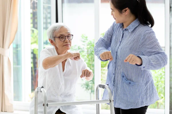 Asiatiska Senior människor sitter slappna av med Walker under rehabilitering och unga vårdare, äldre kvinna eller mor leende och motion med tränare eller dotter hemma, begreppet hälso-och sjukvård — Stockfoto