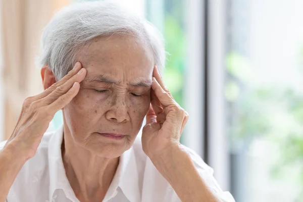 Asiatiska Senior kvinna har huvudvärk, vidrör hennes huvud med händerna, kommunicerar symptomen på Svindel; yrsel; migrän; sjuka deprimerade, äldre personer som lider av huvudvärk smärta eller minnesförlust och sjukdomskänsla — Stockfoto