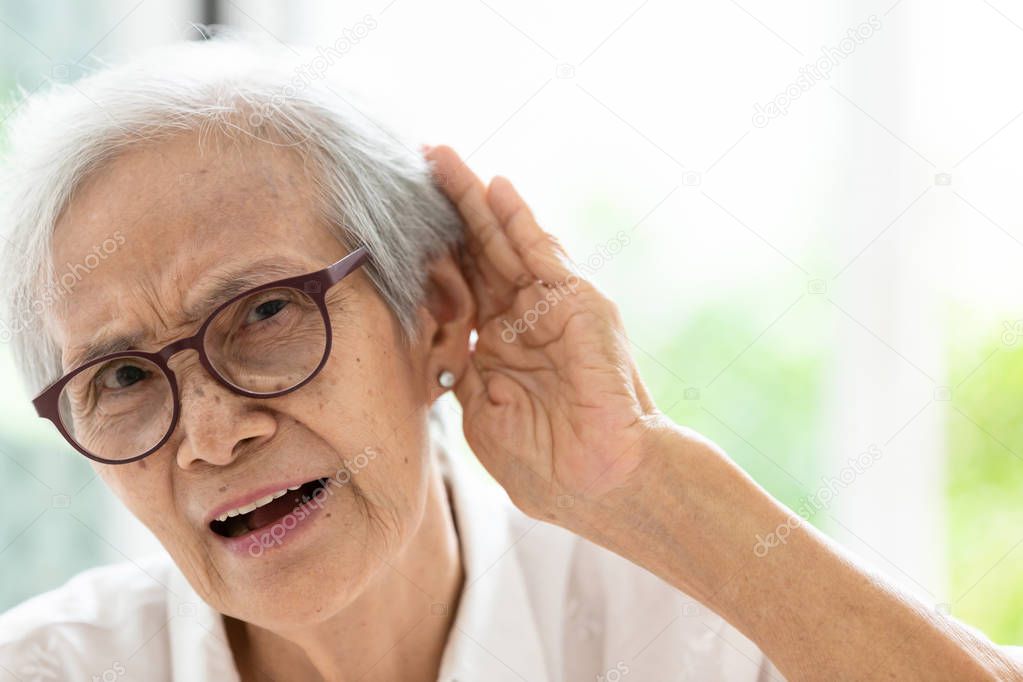 Asian senior woman listening by hands up to the ear,having difficulty in hearing,elderly woman hard to hear,wear glasses with hearing impairment,hearing impaired old people concept