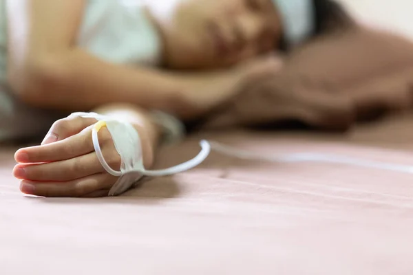 Ασιατικό μικρό κορίτσι με κρύα γέλη τοποθετηθεί στο μέτωπό της για να ανακουφίζει τον πυρετό, το χέρι του χαριτωμένο παιδί με θεραπεία αντικατάστασης υγρού για ασθενή ή αλατούχο ορό σε νοσοκομείο κρεβάτι ή στο σπίτι, υποστήριξη, φροντίδα, ιδέα βοήθειας — Φωτογραφία Αρχείου