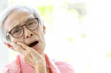 Diş ağrısı muzdarip Asya yaşlı kadın, diş çürümesi, ağrı hissi, el ile yanağını tutan kadın yaşlıinsanlar, diş problemi, diş eti iltihabı, ağrılı ifade ile, diş hekimliği, diş bakımı kavramı
