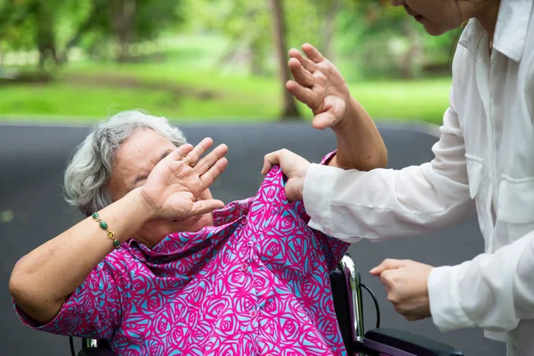 Asya yaşlı kadın fiziksel tekerlekli sandalye istismar edildi, açık parkta saldıran, öfkeli genç kadın ceza yumruk kaldırdı, fiziksel istismar kıdemli insanlar durdurmak, caregiver, Aile durdurma şiddet ve saldırganlık kavramı