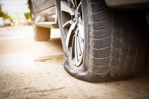 Closeup of car wheel flat tire on the road,car tire leak because  of nail pounding on the street waiting for repair or changing tire,transportation and traveling concept — Stock Photo, Image