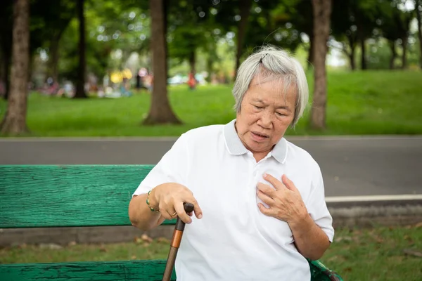 Asian elderly people with certain symptoms,difficulty breathing,suffering or heart problems,Communicates the symptoms of heart disease,senior woman with chest pain suffering from heart attack at outdoor park,healthcare and medical concept