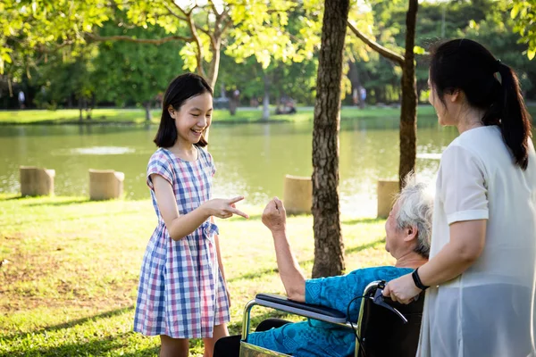 Asiatische Seniorin spielt Steinpapier-Scherenspiel, hat Glück, lächelt mit ihrer Tochter und Enkelin im Rollstuhl im Outdoor-Park, ältere Menschen sind glücklich mit ihrer Familie, Kind hat Spaß, lacht zusammen, glückliches Familienkonzept — Stockfoto